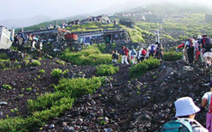 Hikers in trekking gear ascending Mount Fuji’s trail during climbing season — a guided mountain tour offering scenic views and cultural significance in Japan