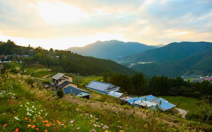 Scenic view of Takahara village on the Kumano Kodo pilgrimage trail in Wakayama, Japan, with traditional countryside homes, terraced rice fields, and lush green mountains.
