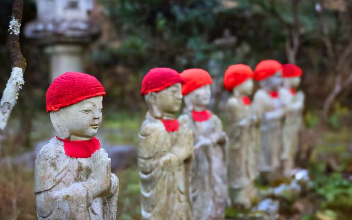 Row of Jizō statues along the peaceful forest trail to Nojiri in Japan—spiritual stone guardians offering protection to travelers on historic pilgrimage and mountain routes.