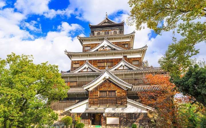 Historic Hiroshima Castle surrounded by trees, a rebuilt 16th-century Japanese fortress known for its samurai heritage and scenic beauty