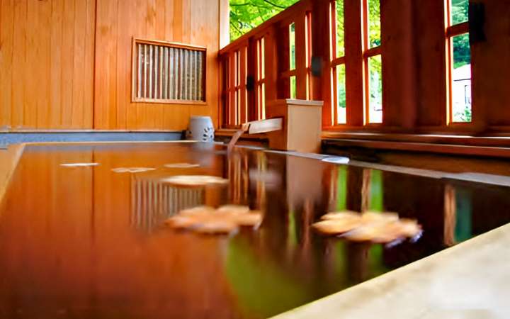 Tranquil outdoor onsen hot spring bath in Kiso-Fukushima, Japan, surrounded by snow-covered mountains and traditional ryokan – a perfect winter relaxation spot on the historic Nakasendo Trail