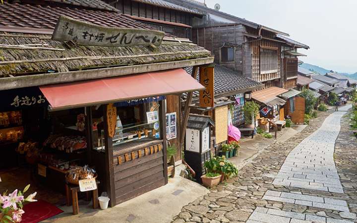 Historic stone-paved street with traditional wooden shops and houses in Tsumago-juku and Magome-juku, a scenic Edo-period post town on the Nakasendo Trail in Japan’s Kiso Valley