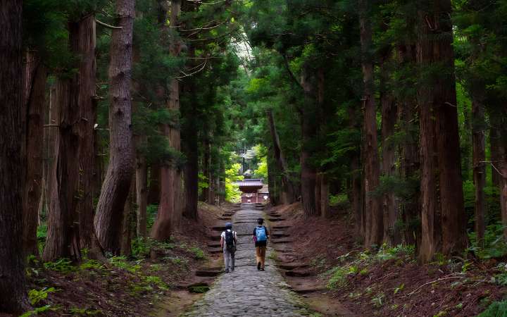Stone path to Hanitsu Shrine in Inawashiro, Fukushima Japan, lined with trees and traditional shrine architecture, historic spiritual travel destination