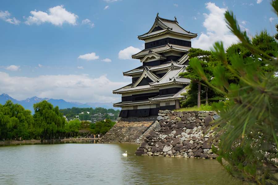 Matsumoto Castle, one of Japan’s best-preserved original castles, reflected in the peaceful moat with the Japanese Alps rising in the background.