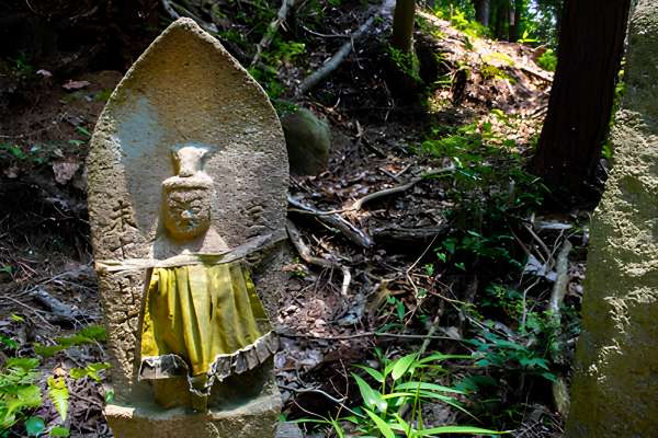 A traditional stone Jizo statue watches over hikers along the historic Nakasendo Minoji Trail, one of Japan’s best-preserved Edo-period walking routes through peaceful cedar forests.